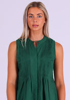 Close up of woman in dark green cotton sleeveless top with high round neckline and decorative pleats