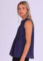 Model wears dark blue sleeveless cotton top that covers the hips, with tiny pleats across bust that make the lower half a relaxed fit