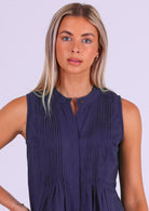 Close up of woman in dark blue cotton sleeveless top with high round neckline and decorative pleats