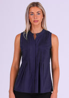 Woman in dark blue sleeveless cotton top that buttons through the front with hidden button and one visible at the front of the neckline