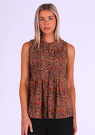 Model poses in warm Indian floral print sleeveless cotton top with high round neckline and tiny pleats across bust