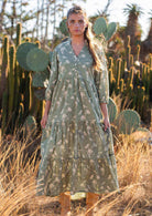 Model wears cotton maxi dress with tiered skirt and buttoned bodice that forms a V-neckline