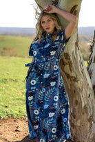 Model standing wearing floral print Chelsea Dress  100 percent cotton shirt dress with pockets and waist tie