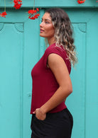 Woman stands sideways in deep red cotton gauze top with cap sleeves