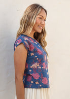 Woman wears lightweight 100% cotton blue floral top with cap sleeves and round neckline