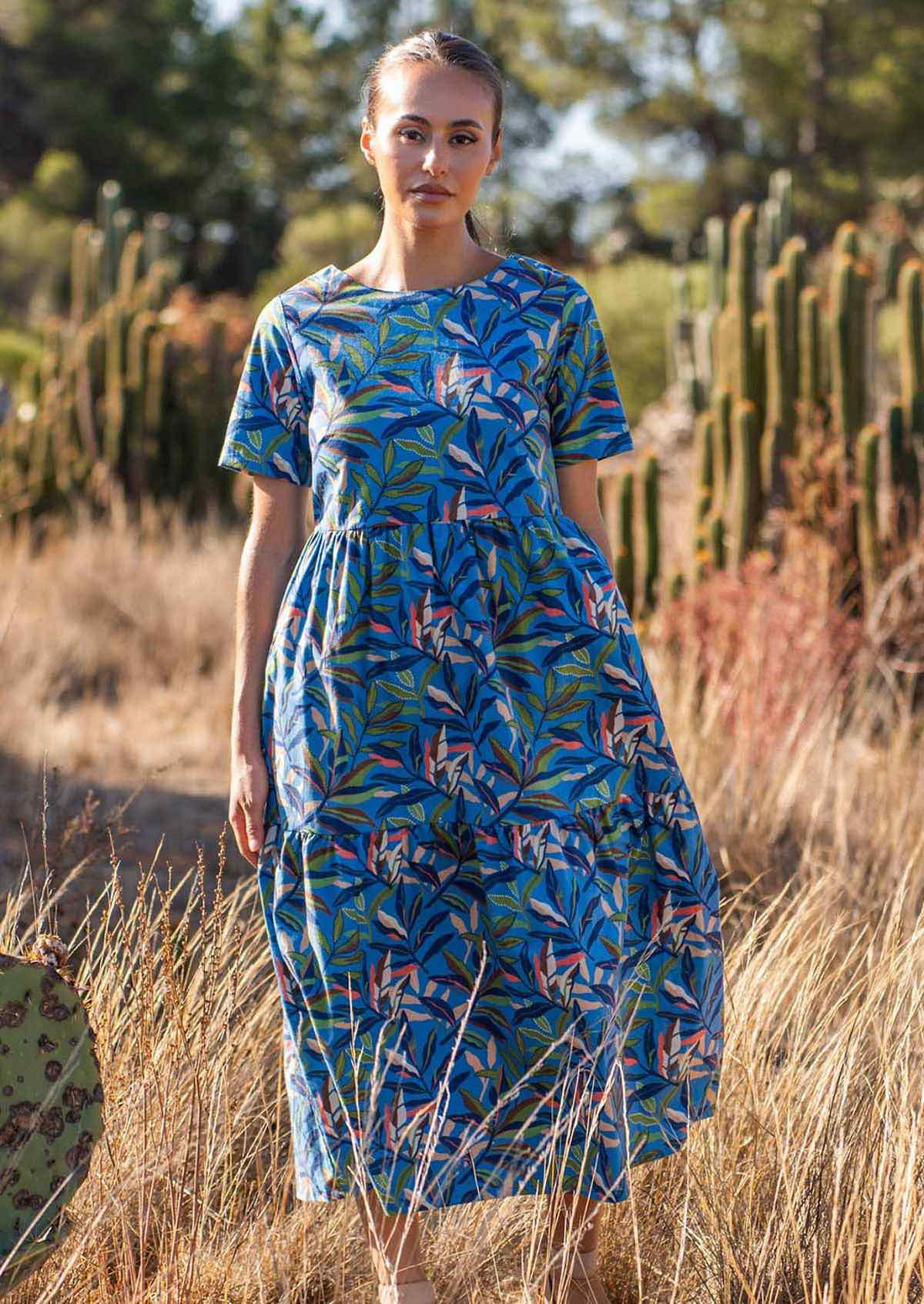 Woman wears cotton short sleeve midi length dress with high round neckline and tiered skirt