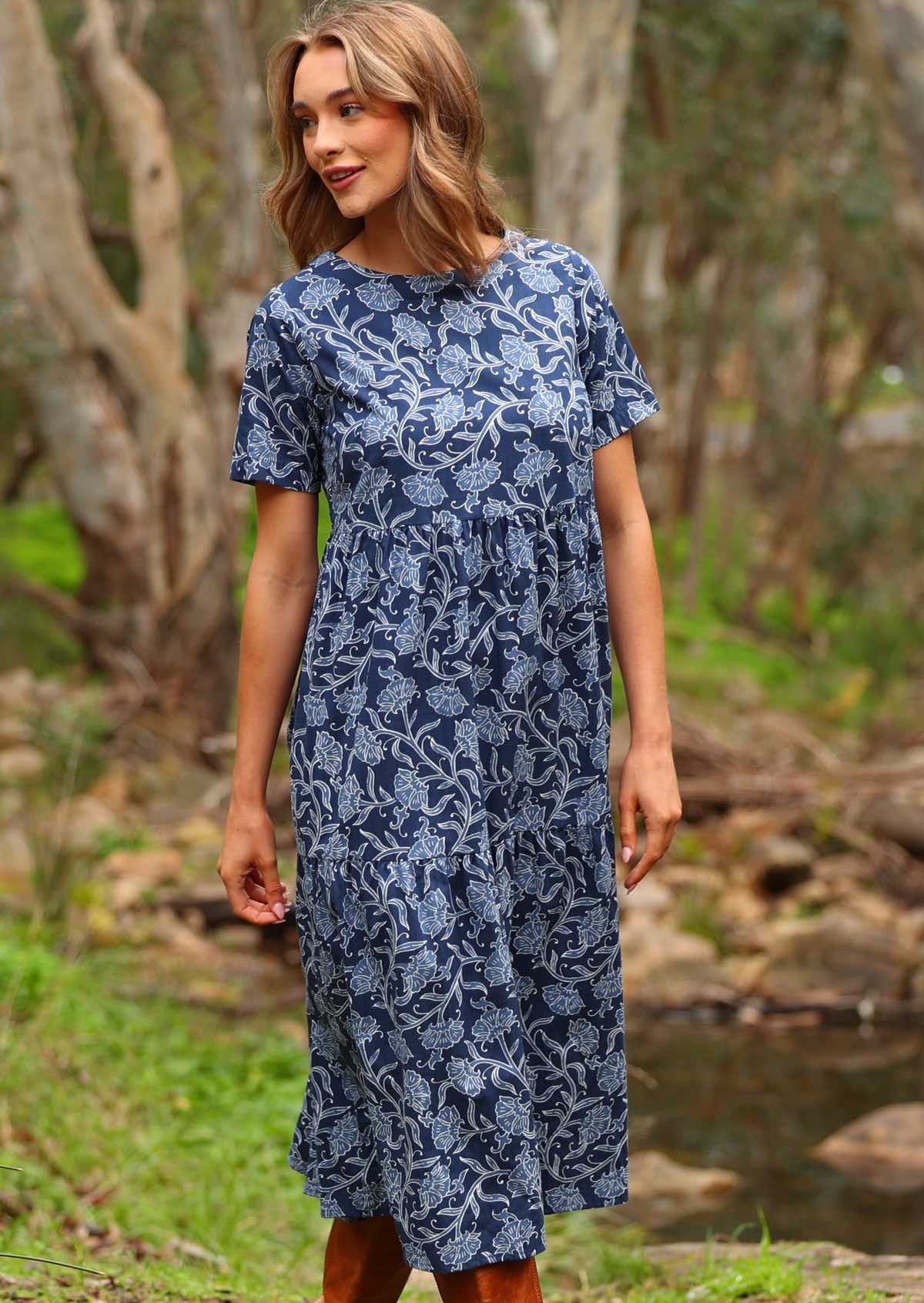 Model standing wearing Claudia Dress Neela navy blue 100 percent cotton maxi sundress paired with tan leather boots