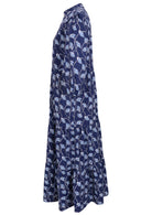 Side view of a full length maxi dress with 3 tiered flowy skirt, mandarin collar, buttoned bodice and pockets