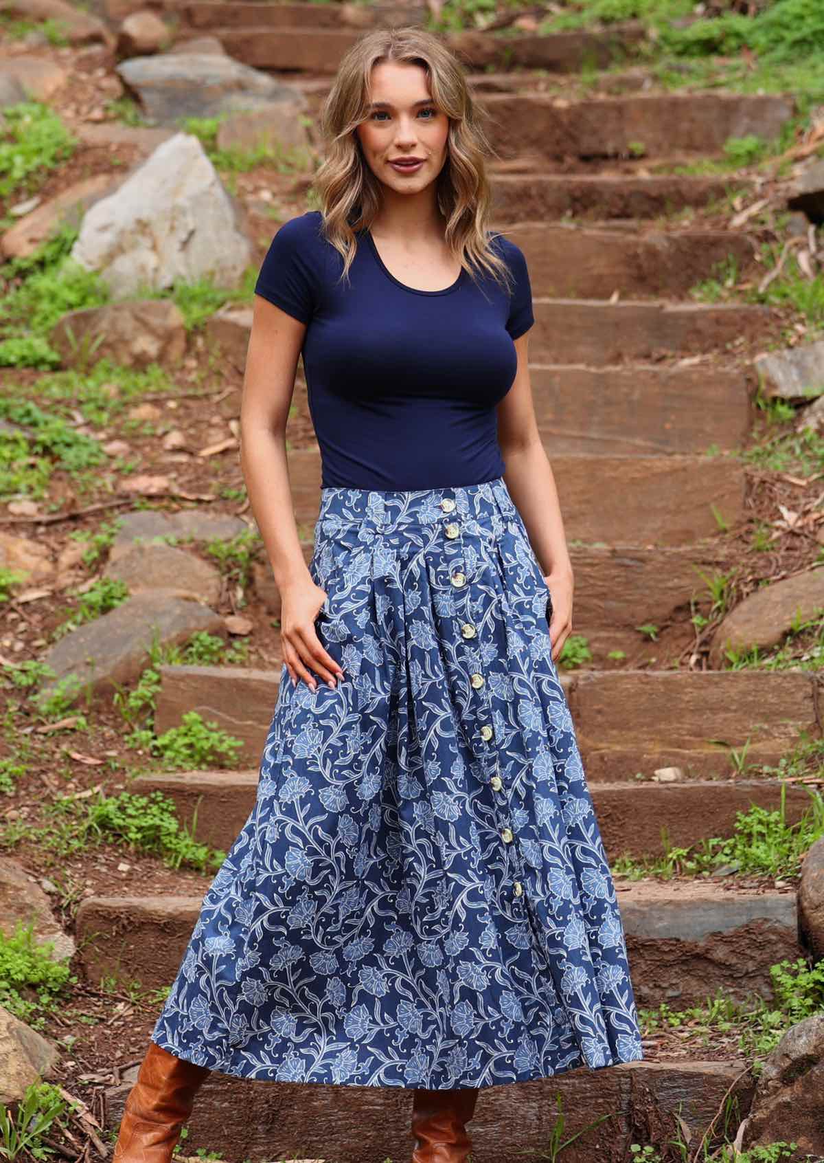 Model standing wearing Cora Skirt Neela navy button down cotton maxi skirt with thumbs in pockets