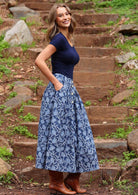 Model posing side on wearing Cora Skirt Neela navy button down cotton maxi skirt with hands in pockets