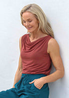 Woman wearing a terracotta coloured singlet top paired with teal pants