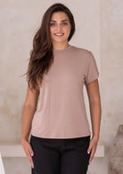 Woman wearing a fawn t-shirt with a high crew neckline and black pants