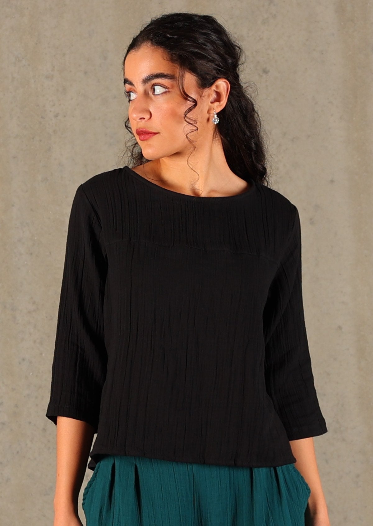 Model wears black double cotton top with 3/4 sleeves and high round neckline