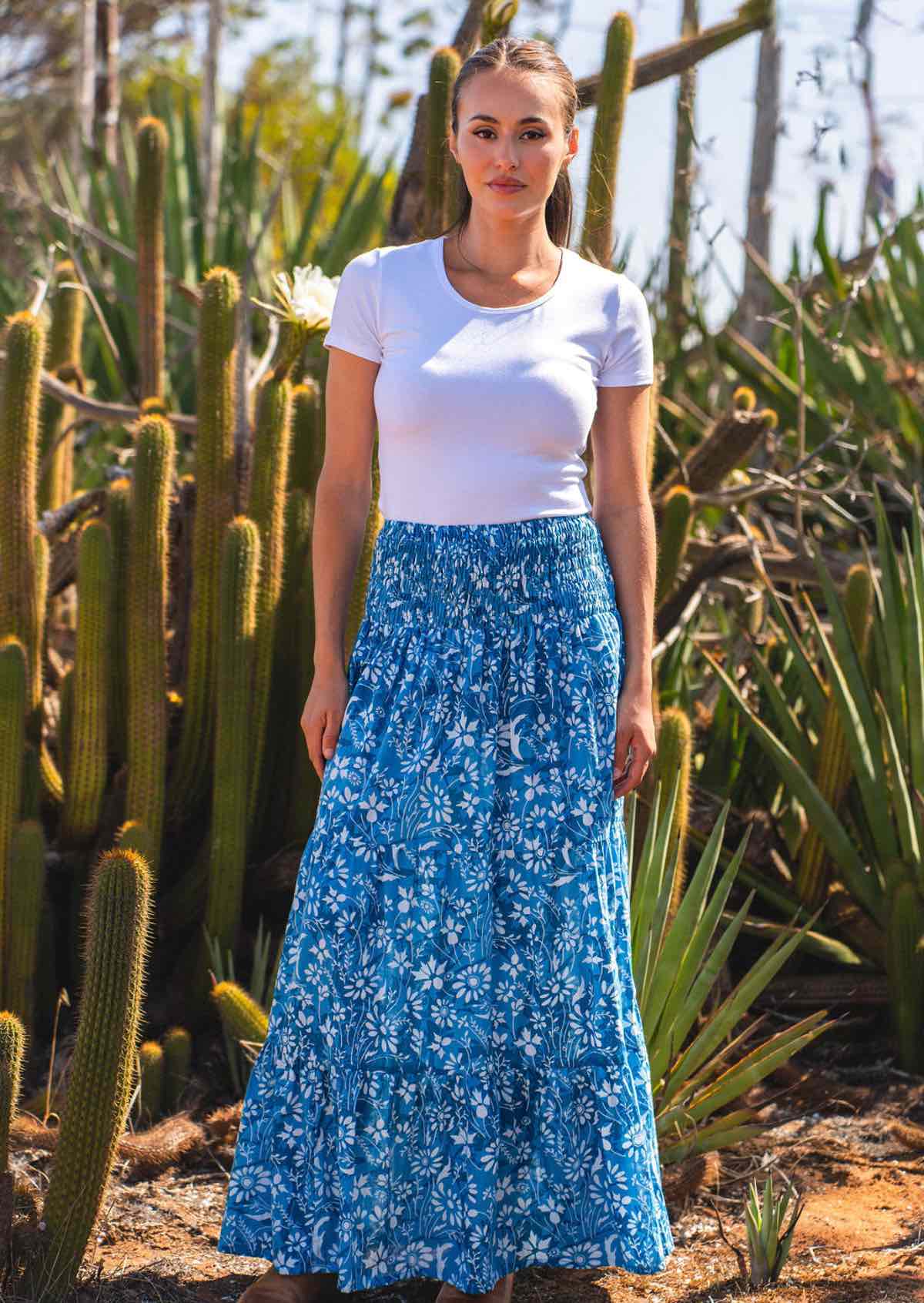 Woman wears cotton tiered maxi skirt with wide elasticated waistband, in a floral print in hues of blue