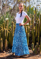 Woman wears cotton tiered maxi skirt in gorgeous white and dark blue graphic florals and leaves on a pale blue base