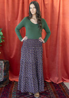 Woman wearing a cotton maxi skirt with wide elastic shirred waistband, in dark purple based floral pattern.
