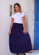 Woman wearing navy blue cotton maxi skirt with elastic waist and white t-shirt in front of white wall