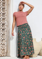 Model posing in 100% cotton tiered maxi skirt with vibrant floral print on dark green base.