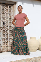 Woman wears cotton tiered maxi skirt in green based floral print with wide elastic shirred waistband.
