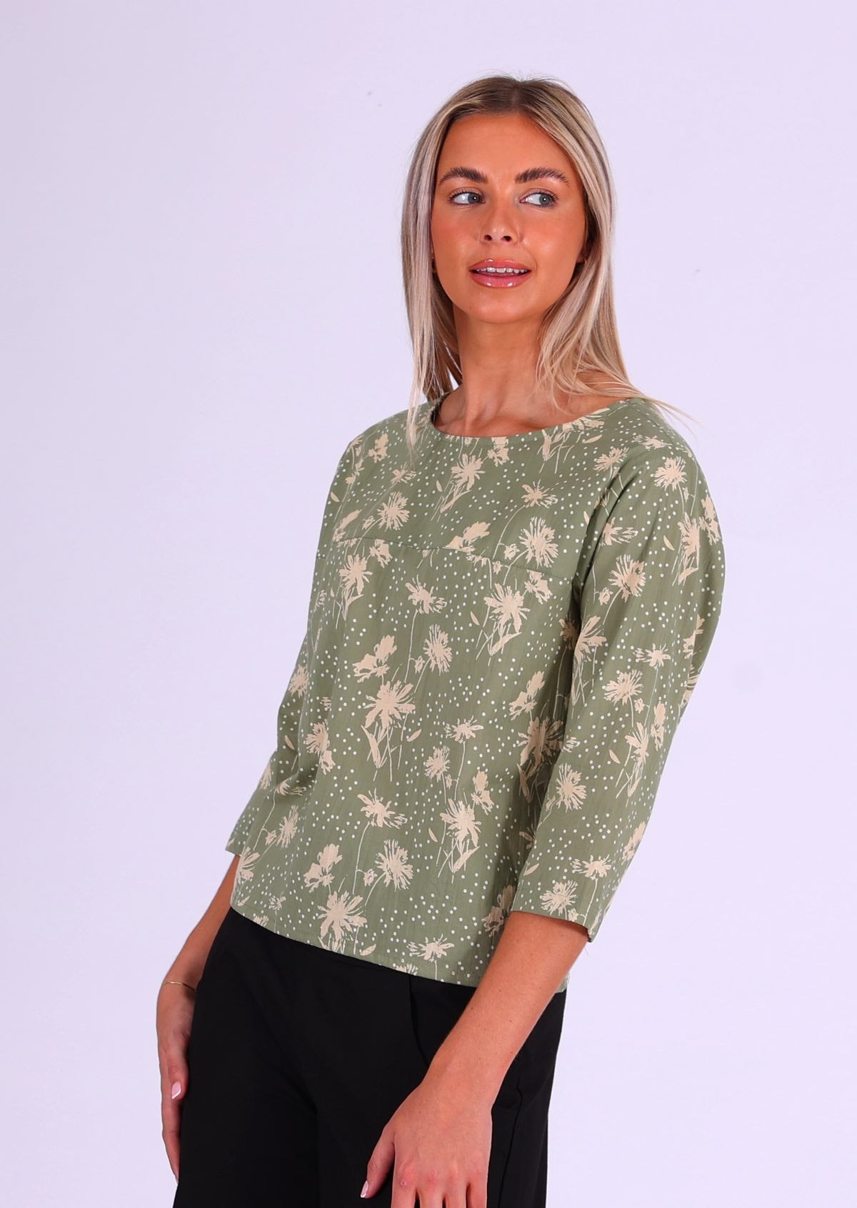 Woman stands sideways in cotton loose fit top with 3/4 sleeves and round neckline