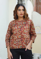 Model wears relaxed fit cotton top with 3/4 sleeves and round neckline in earthy toned, red based floral print 