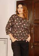 Model in loose fit cotton top with maroon and cream floral print on black base.
