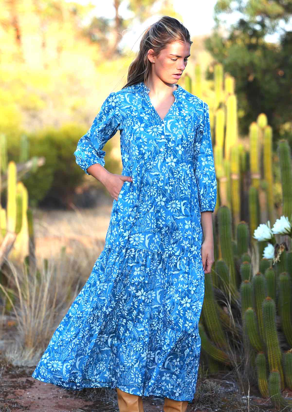 woman in blue cotton maxi dress with light blue and white floral print with hand in pocket