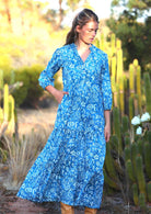 woman in blue cotton maxi dress with light blue and white floral print with hand in pocket