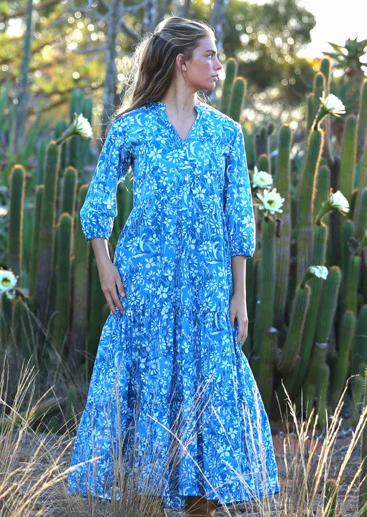 woman in blue cotton maxi dress with light blue and white floral print with pockets and long sleeves
