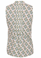 The back view of the white sleeveless blouse features yellow and green floral print and vertical pleats in the centre back