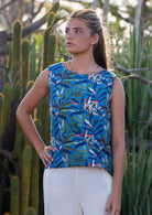 Model standing in front of cactus plants wearing 100 percent cotton blue leafy print sleeveless top with high round neckline