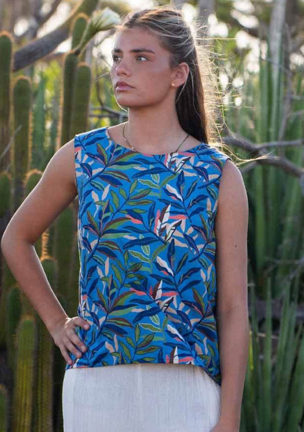 Model standing in front of cactus plants wearing 100 percent cotton blue leafy print sleeveless top with high round neckline and hand on hip