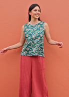 Model stands in sleeveless cotton top in green based floral print, with terracotta cotton wide leg pants