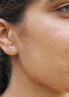 Close-up of a person wearing a musical eight note sterling silver studs with butterfly backs 