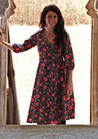 Model wearing 3/4 sleeved navy blue based cotton wrap dress with V-neckline and pockets.