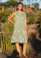 Model wears cotton sleeveless relaxed fit dress with tiered skirt that falls to the knee and hidden side pockets