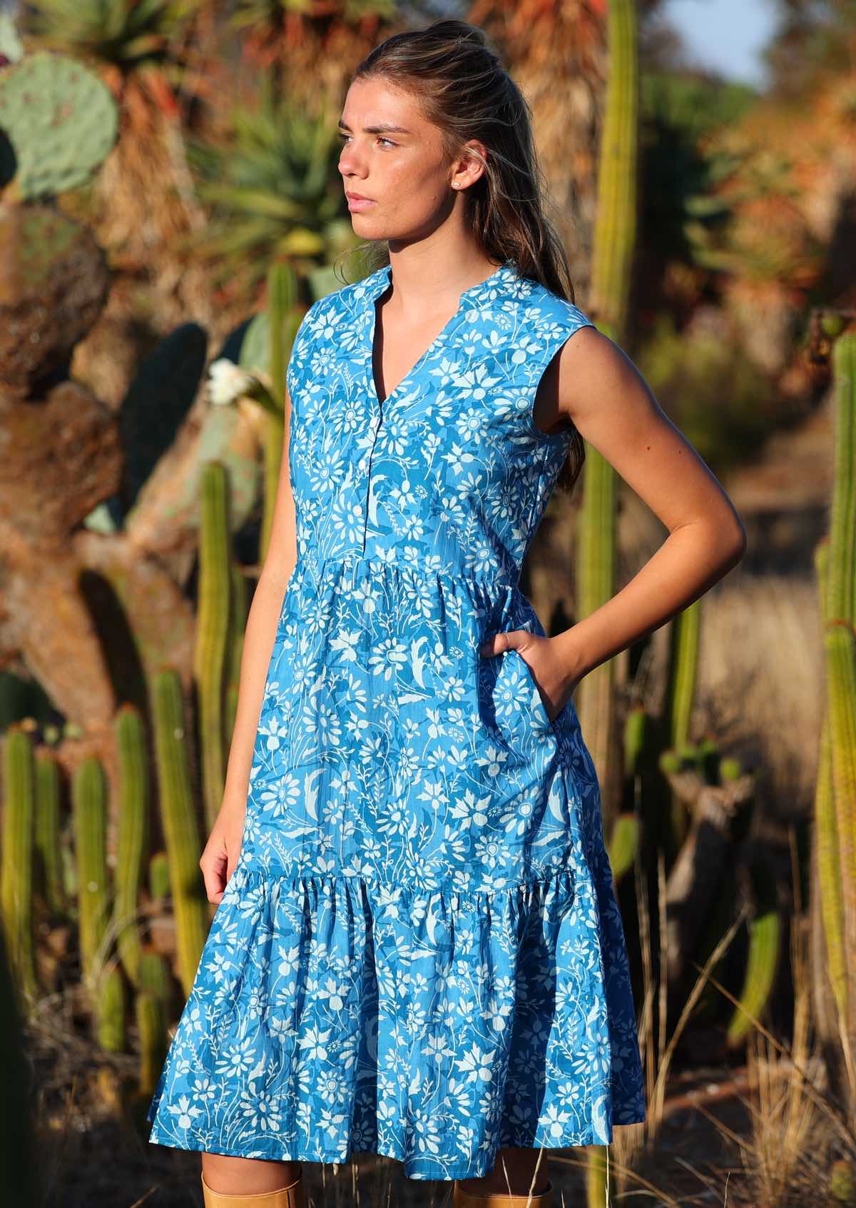 woman in blue floral cotton midi dress with hand in pocket in front of cactus 