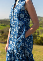 Close up of woman in cotton sleeveless dress with buttoned bodice, V-neckline and mandarin collar, with her hand in side pocket