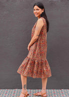 Model standing side on wearing Wild Spice print midi length sleeveless Indian cotton sundress