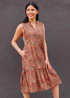 Model standing with one hand in pocket wearing Wild Spice print midi length sleeveless Indian cotton sundress