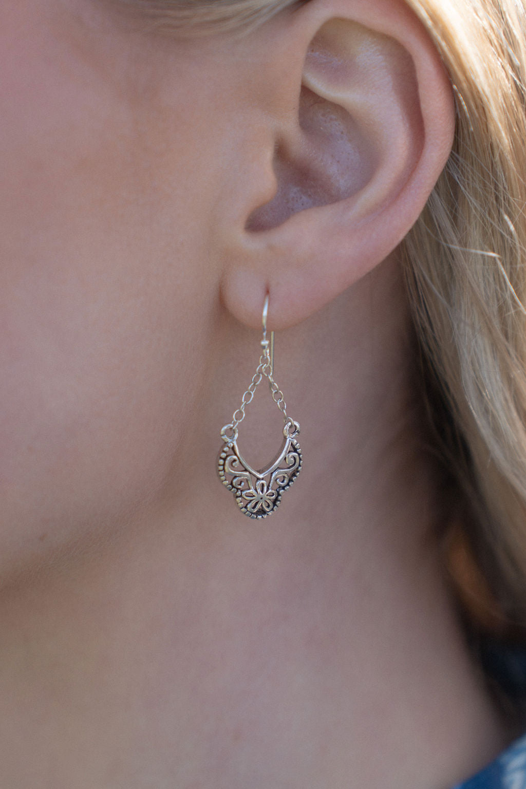 close up of silver dangly earring in woman's ear