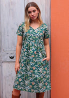 Model standing with one hand in pocket modelling the Etta v-neck Dress Flannel Flower cotton green sundress with short sleeves