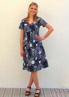 Woman wears cotton knee length dress with empire waistline in bold blue floral print