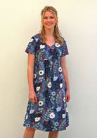 Woman wears relaxed fit cotton dress with V-neck and short sleeves, length is over the knee