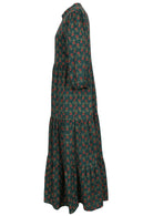 Side view of a full length maxi dress with 3 tiered flowy skirt, mandarin collar, buttoned bodice and pockets