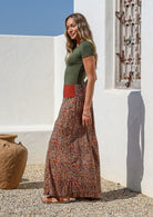 Woman wearing a green top and wide legged patterned cotton pants standing in side on 