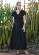 Woman wears black rayon wrap maxi dress with butterfly sleeves and attached waist ties