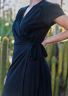 Close up of black rayon wrap dress which forms a V-neckline, secured with attached waist ties