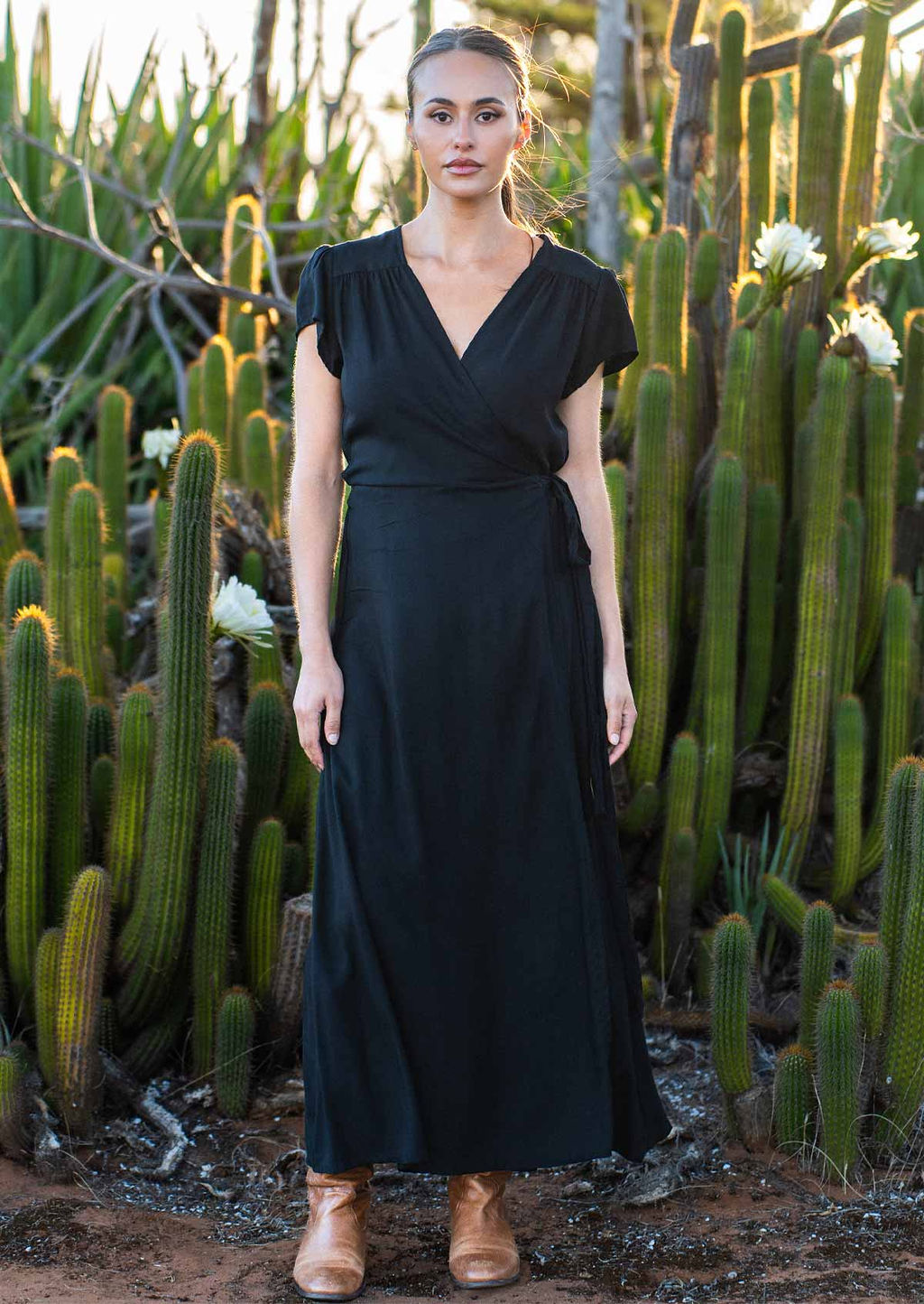 Woman wears soft, non-stretch, black rayon maxi wrap dress with gathers at front of shoulders