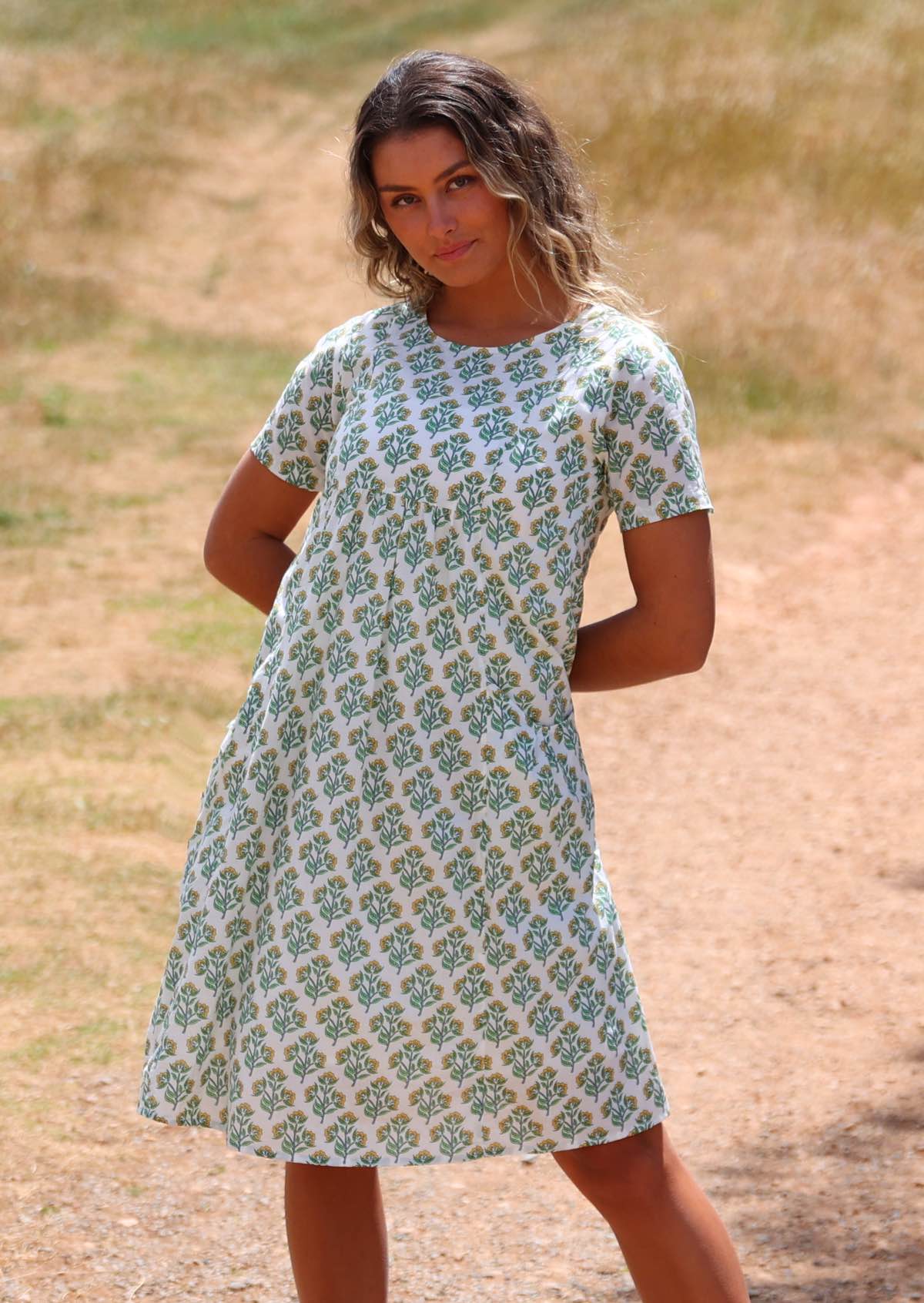 Woman wearing white cotton dress with floral pattern on grassy hill